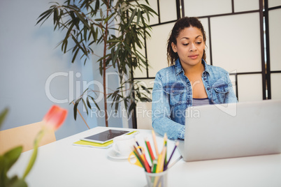 Confident executive using laptop at creative office