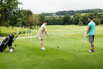 Male instructor assisting woman in learning golf