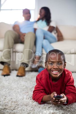 Boy holding remote while lying on the floor