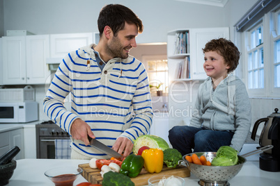 Boy looking while father chopping vegetables