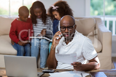 Man talking on mobile phone while checking bills