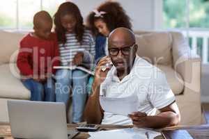 Man talking on mobile phone while checking bills