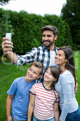 Happy family taking a selfie from mobile phone in park