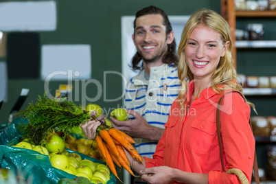 Happy couple selecting fruits and carrots in organic section