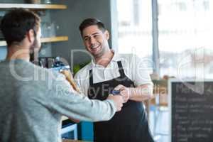 Waiter giving bread to customer at counter
