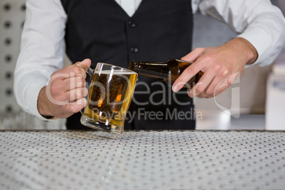 Bartender pouring beer on glass