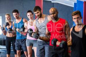 Portrait of serious friends lifting dumbbells in gym