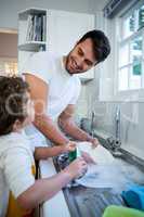 Son helping father in washing utensils