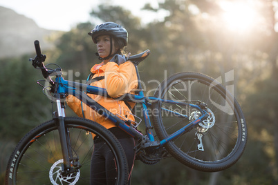 Female biker carrying mountain bike