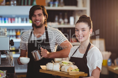 Portrait of waiter and waitress holding plate of meal and coffee jug