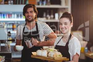Portrait of waiter and waitress holding plate of meal and coffee jug