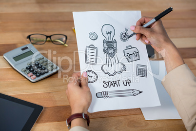 Businesswoman drawing icons on paper
