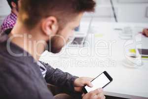 Executive using mobile phone in meeting at creative office