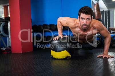 Shirtless athlete doing push-ups with exercise ball