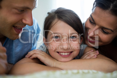 Parents and daughter lying in bedroom