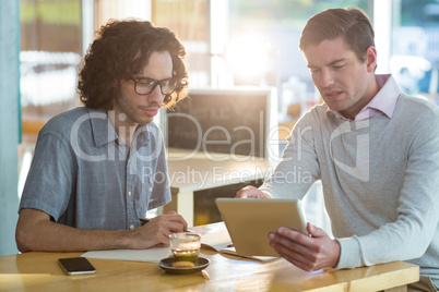 Male friends discussing on digital tablet