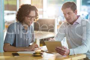 Male friends discussing on digital tablet