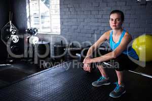 Portrait of female athlete sitting on barbell