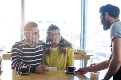 Waiter serving a cup of coffee to customer