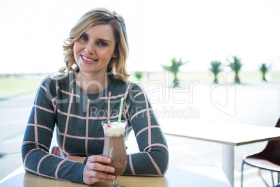 Smiling woman sitting in cafeteria and having milkshake Smiling woman sitting in cafeteria and having milkshake