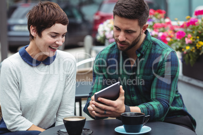 Businesspeople using digital tablet while having coffee