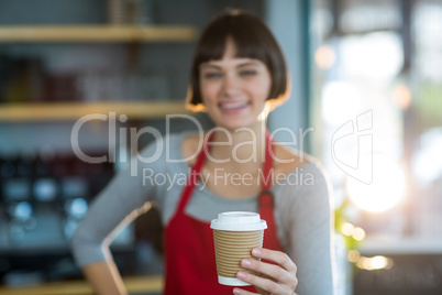 Portrait of waitress holding disposable cup of coffee