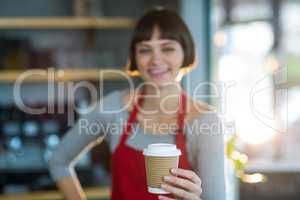 Portrait of waitress holding disposable cup of coffee