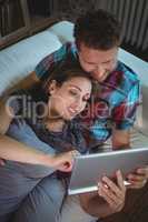 Happy couple using digital tablet in living room