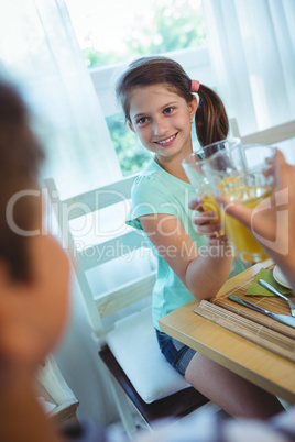 Smiling girl toasting glass of orange juice