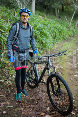 Portrait of male mountain biker with bicycle in the forest