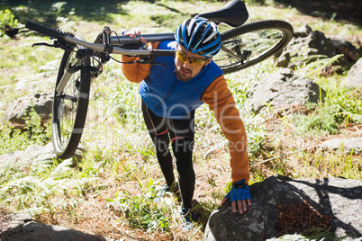 Male mountain biker carrying bicycle in the forest