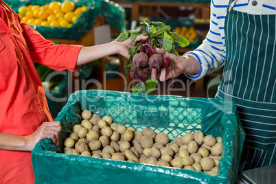 Staff assisting woman in selecting fresh beetroots