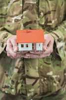 Mid section of soldier holding a model home