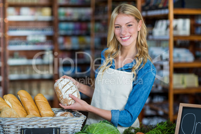 Smiling staff holding bread in organic section