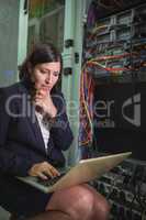 Technician using laptop while analyzing server