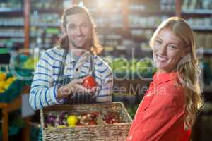 Male staff assisting woman in selecting fresh vegetables