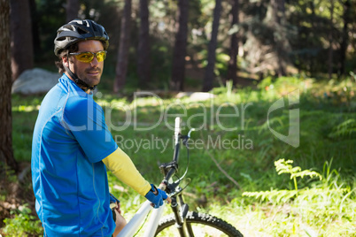 Portrait of male mountain biker with bicycle in the forest