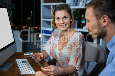 Businesswoman discussing with colleague over digital tablet