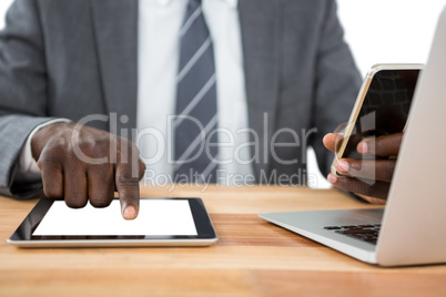 Mid section of businessman using digital tablet and other multimedia devices