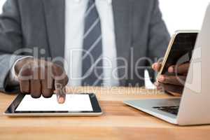 Mid section of businessman using digital tablet and other multimedia devices