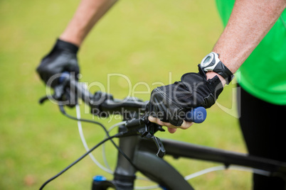 Male athletic standing with mountain bike in park
