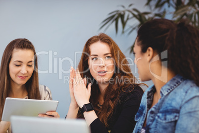 Businesswomen discussing at desk while using digital tablet
