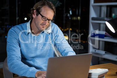 Businessman talking on phone while working in office