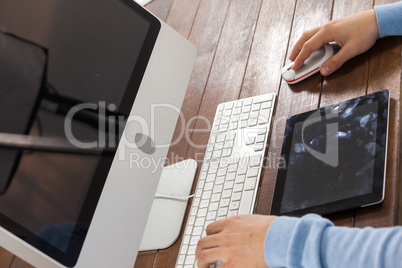 Man using laptop while writing on notepad