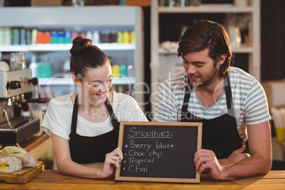 Waiter and waitress holding chalkboard at counter