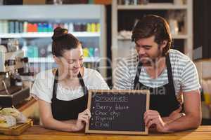Waiter and waitress holding chalkboard at counter