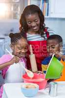 Children preparing cake with their mother