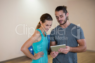 Fitness trainer showing digital tablet to woman