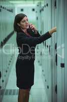 Technician talking on mobile phone while analyzing server