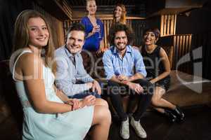 Smiling friends sitting together in sofa